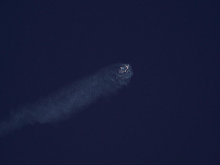 Bright celestial body streaks through dark night sky leaving a smoky trail.